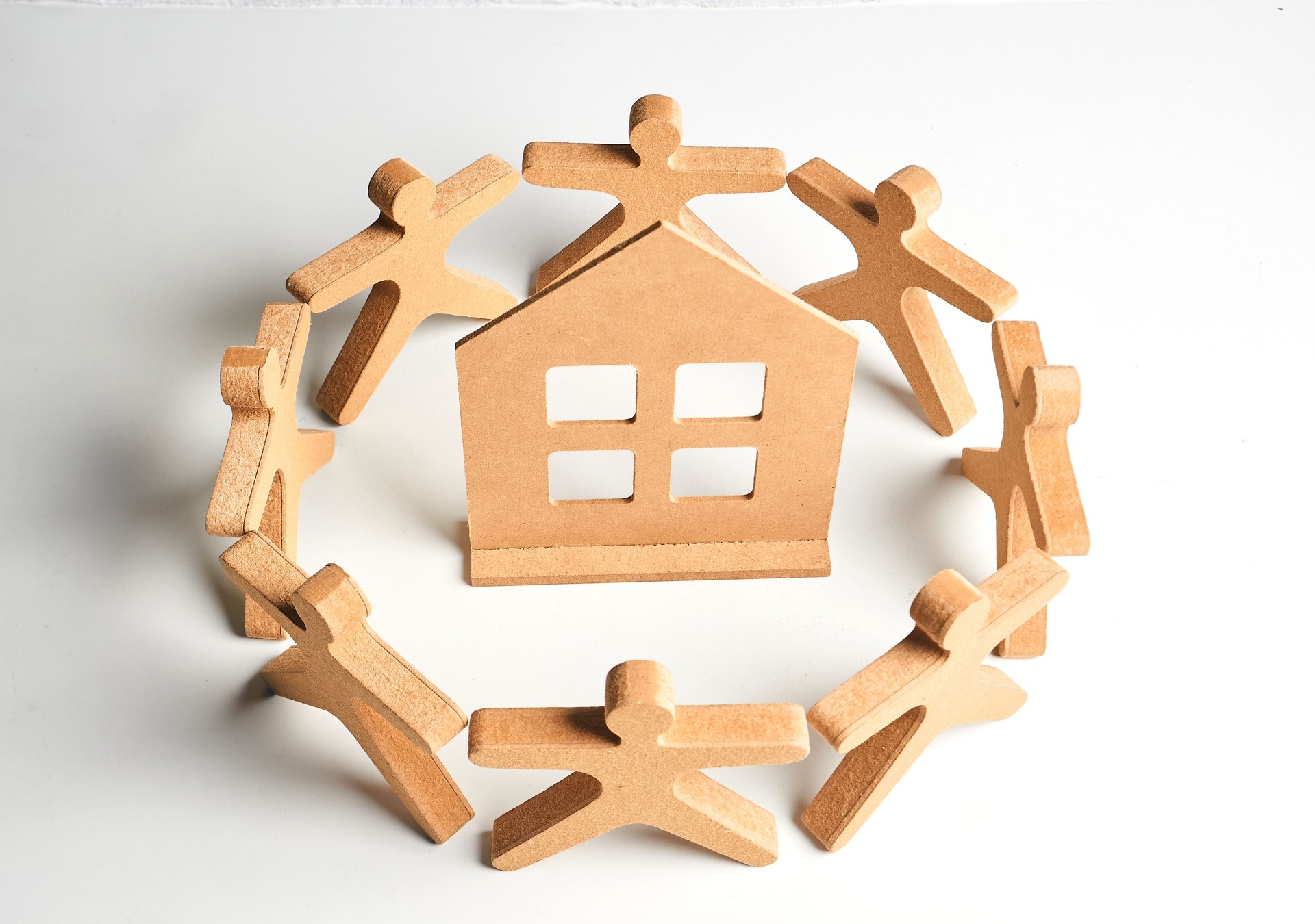 Wooden figures forming a protective circle around a house, symbolizing neighborhood support, safe housing and community care. Wooden figures forming a protective circle around a house, symbolizing neighborhood support, safe housing and community care.